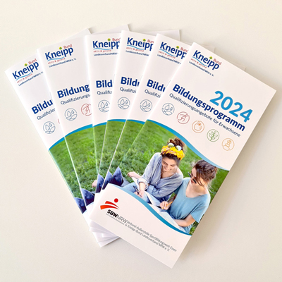Die Programmhefte des Kneipp-Bildungsprogramms 2024 liegen aufgefächert übereinander.