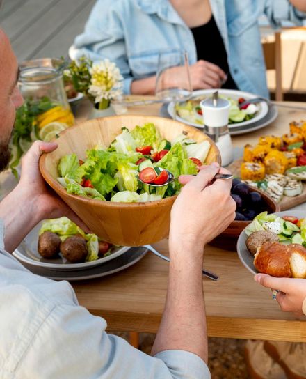 salatschüssel mit salat, die über einen reich gedeckten tisch gehalten wird
